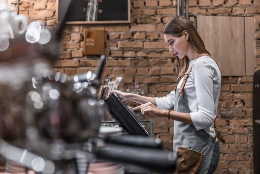 A woman using a POS system for liquor inventory management. 